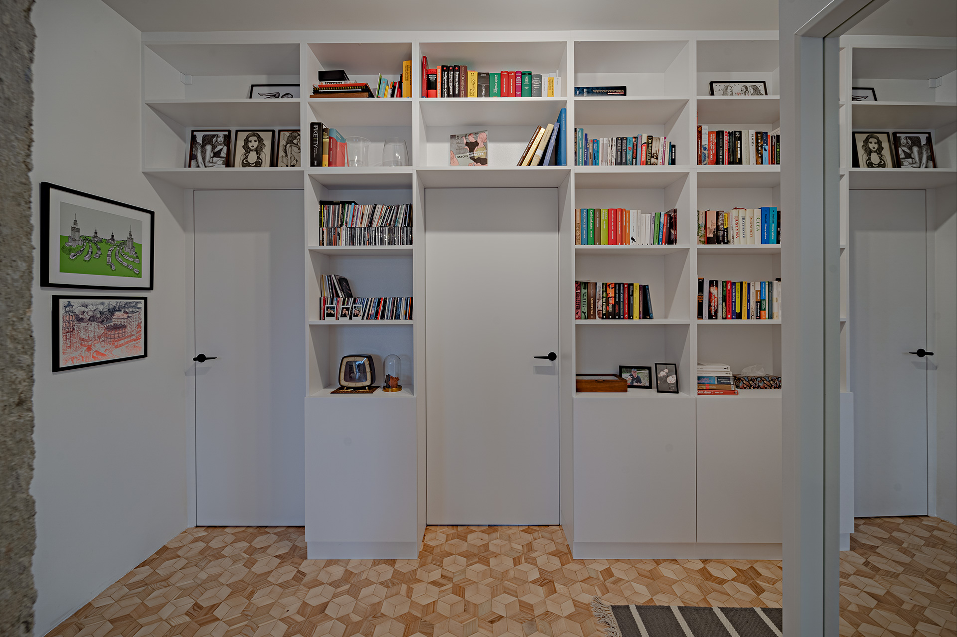 Sąsiadujący z salonem obszerny korytarz stał się idealnym miejscem do wyeksponowania książek i rodzinnych pamiątek.