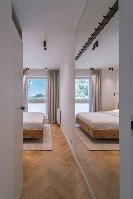 Projekt minimalistycznego wnętrza na Mokotowie w stylistyce nawiązującej do lat 60tych &ndash; lustro w sypialni ma zintegrowane wieszaki na ubrania