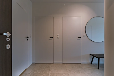 Projekt minimalistycznego wnętrza na Mokotowie w stylistyce nawiązującej do lat 60tych &ndash; zamknięte drzwi z ukrytą ościeżnicą prowadzące do sypialni i gabinetu