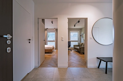 Projekt minimalistycznego wnętrza na Mokotowie w stylistyce nawiązującej do lat 60tych &ndash; otwarte drzwi z ukrytą ościeżnicą prowadzące do sypialni i gabinetu