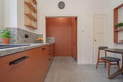 Projekt kuchni w modernistycznej willi pod Warszawą - paleta barwno-materiałowa kuchni to połączenie koloru terakoty z szarością lastryko oraz dodatkami drewna i szkła.