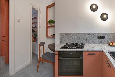 Projekt kuchni w modernistycznej willi pod Warszawą &ndash; drzwi do spiżarni wyposażonej w stosowne regały. Widok na ceramiczne kinkiety: wsp&oacute;łczesne, ale stylizowane na historyczne oprawki oświetleniowe