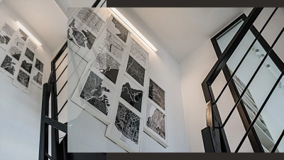 Projekt wnętrz domu w bieli i drewnie z czarnymi dodatkami &ndash; ekspozycja grafiki w klatce schodowej