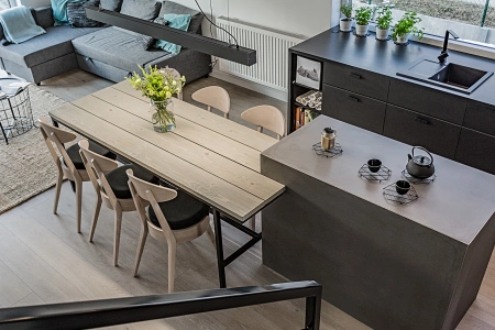 Projekt wnętrz domu w bieli i drewnie z czarnymi dodatkami – wyspa kuchenna z impregnowaną, betonową okładziną