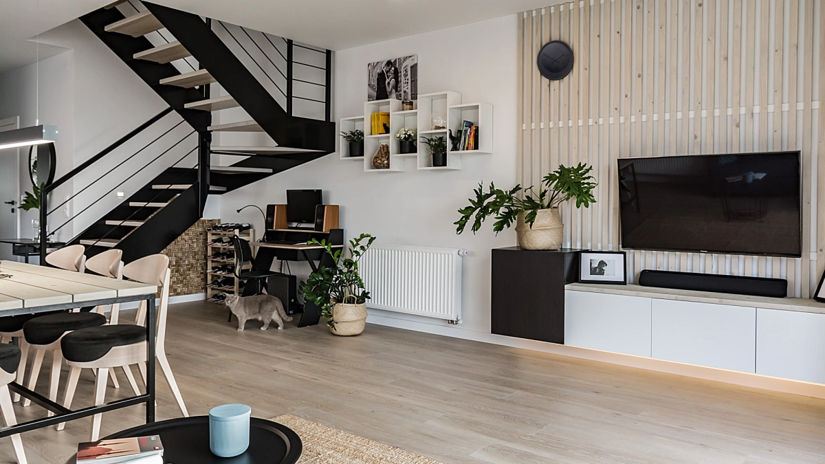 Projekt domu w bieli i drewnie z czarnymi dodatkami – na parterze salon z aneksem kuchennym, jadalnią i schodami