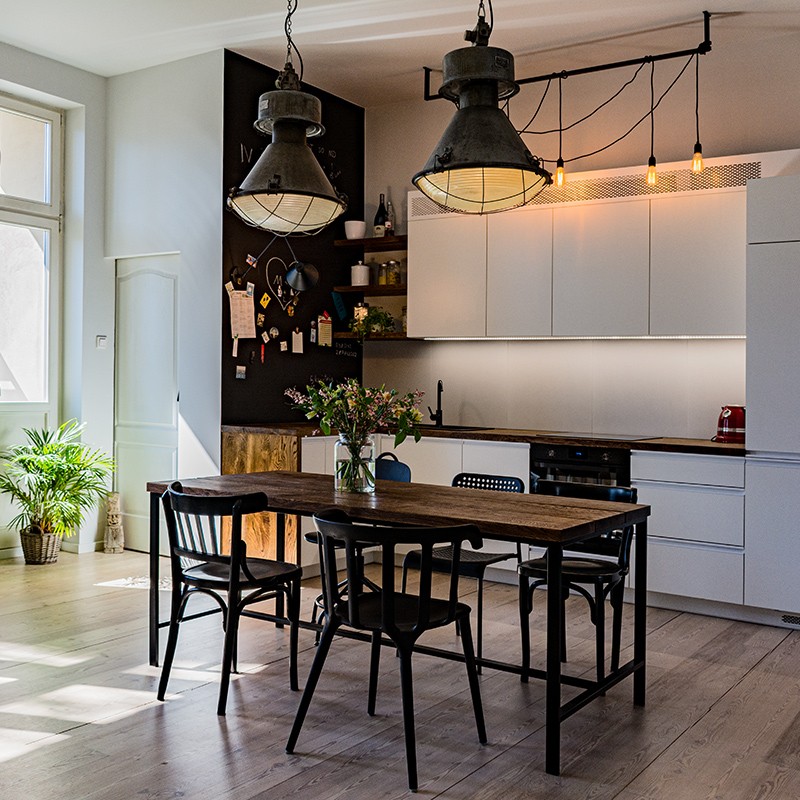 Renowacja aneksu kuchnego w mieszkaniu w stuletniej kamienicy: industrialne lampy, naturalne deski, odnowione podłogi – dla małżeństwa artystów